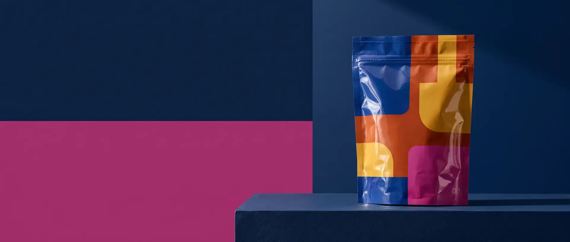 A glossy printed retort pouch on a navy and magenta set